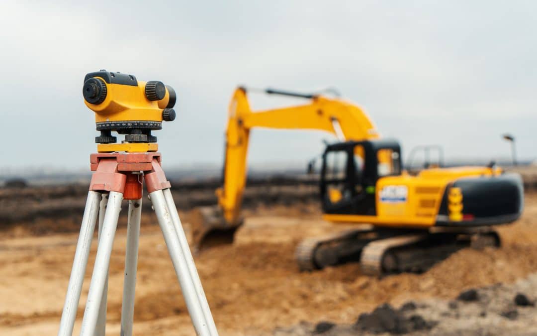 Surveying equipment on build site with excavator in background